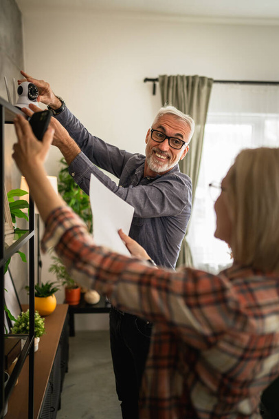 Pari kotona kypsä tai vanhempi valkoihoinen aviomies ja vaimo yhdistää ja asentaa CCTV-valvontakameran - Valokuva, kuva