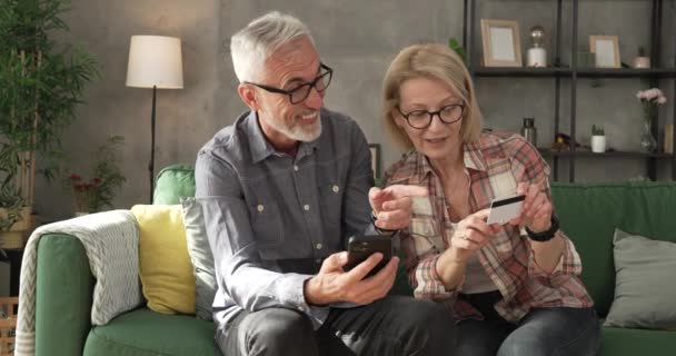 ώριμο ζευγάρι ή ηλικιωμένοι σύζυγοι που ψωνίζουν online κάθονται στο σπίτι - Πλάνα, βίντεο