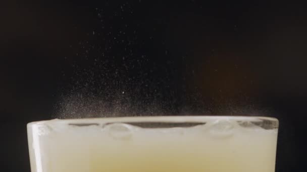 Una cima di vetro d'acqua e medicamento dissolto o vitamina solubile su uno sfondo scuro. Il farmaco in schiume di reazione chimica, produce massa liquida gialla, bolle e micro spruzzi. Il - Filmati, video