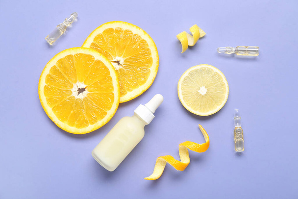 Пляшка і ампули вітаміну С зі скибочками цитрусових на бузковому фоні - Фото, зображення