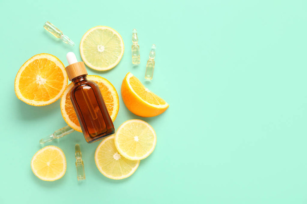 Fles en ampullen van vitamine c met citrusschijfjes op turquoise achtergrond - Foto, afbeelding
