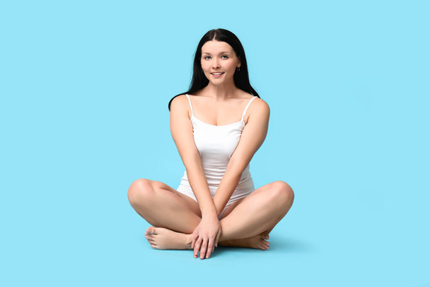 Tělo pozitivní žena ve spodním prádle sedí na modrém pozadí - Fotografie, Obrázek