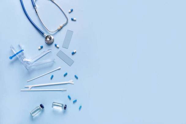 Estetoscopio con espéculo ginecológico, herramientas de prueba de Papanicolaou y pastillas sobre fondo azul - Foto, imagen