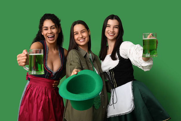 Schöne junge Frauen mit Biergläsern auf grünem Hintergrund. St. Patrick 's Day Feier - Foto, Bild