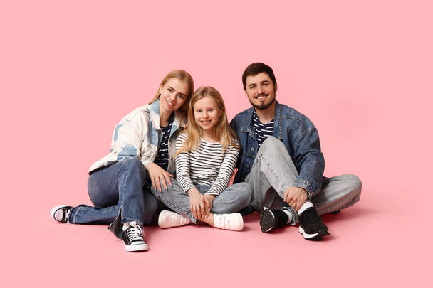 Happy family in stylish denim clothes sitting on pink background - Photo, Image