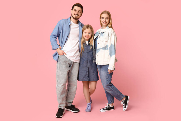 Famiglia felice in abiti eleganti in denim su sfondo rosa - Foto, immagini