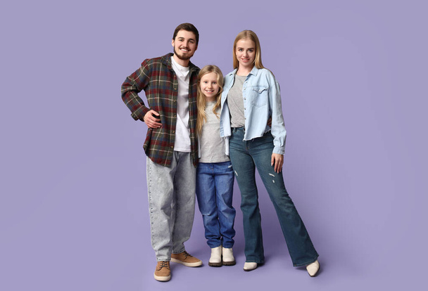 Familia feliz en ropa de mezclilla con estilo sobre fondo púrpura - Foto, imagen