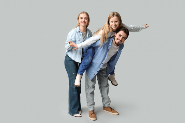 Glückliche Familie in stylischer Jeanskleidung, die gemeinsam Spaß auf grauem Hintergrund hat - Foto, Bild