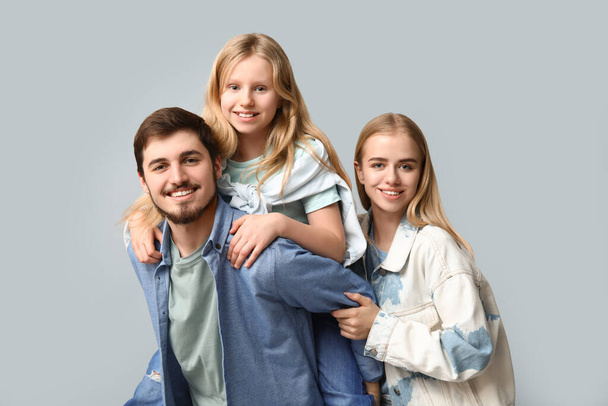 Famille heureuse dans des vêtements en denim élégant s'amuser ensemble sur fond gris - Photo, image