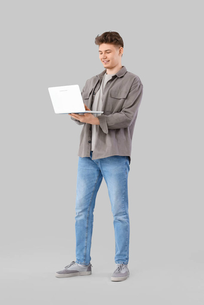 Młody człowiek korzystający z laptopa na jasnym tle - Zdjęcie, obraz