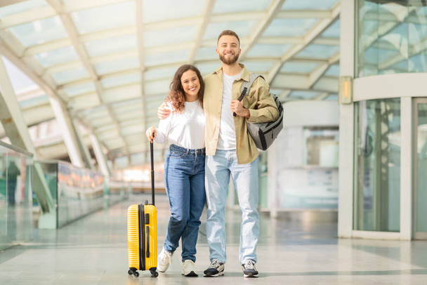 空港の廊下で手を歩く若いカップル笑顔は一緒に旅行する喜びを意味します - 写真・画像