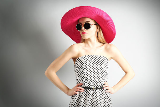 Expressive young model in pink hat with sunglasses on gray background - Foto, immagini