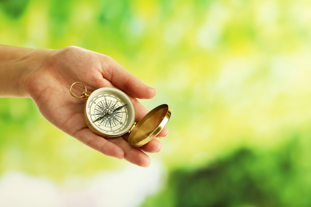 Female hand with compass on bright blurred background - Fotoğraf, Görsel