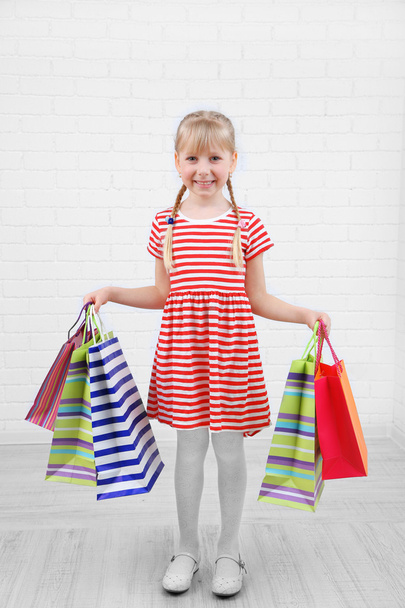 Beautiful little girl with shopping bags in room - Foto, Imagem