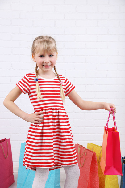 Beautiful little girl with shopping bags in room - Photo, Image