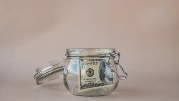 Stop motion of Dollar banknote saving money in glass jar. Consumption and economy Collecting money. Tips. Business, finance, saving, banking and people concept. Extra money, passive  - Footage, Video