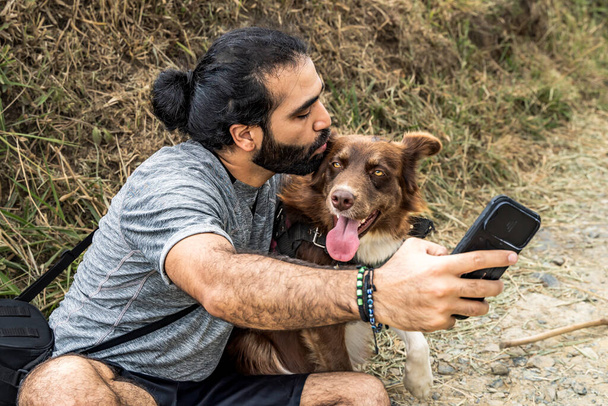 adulte mâle mestizo prendre un selfie avec son collie frontière chien et embrasser sa tête - Photo, image