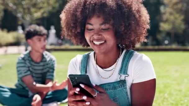 Μαύρη γυναίκα, φοιτήτρια και γελάει με το τηλέφωνο για τα μέσα κοινωνικής δικτύωσης, επικοινωνία ή δικτύωση στο υπαίθριο πάρκο. Αφρικανική γυναίκα με άφρο, χαμόγελο ή κινητό smartphone για online chat στο πεδίο. - Πλάνα, βίντεο
