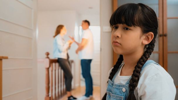 Stresli ve mutsuz genç kız arka planda ebeveynleri tartışırken köşede ağlayıp üzülüyor. Evde aile içi şiddet ve travmatik çocukluk depresyona dönüşür. Eşzamanlama - Fotoğraf, Görsel