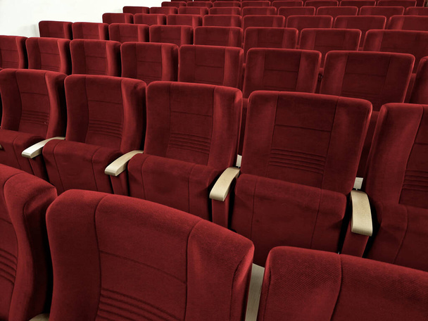 Sıralar dolusu yastıklı koltuk. Koltuklar sıra sıra dizilmiş koltuklar ve koltuklar sahneye doğru uzanan bir amfitiyatro eğiminde yere yapışıktır. kırmızı süet kumaş - Fotoğraf, Görsel