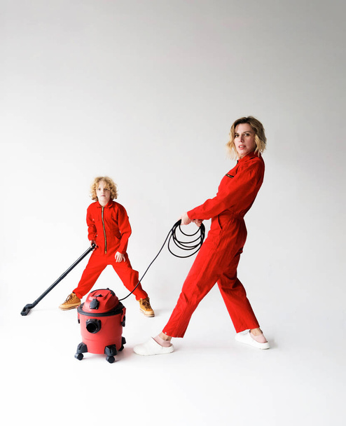 mamá y su hijo en mono rojo sobre un soporte de fondo aislado blanco junto a un tema de limpieza y aspiradora - Foto, Imagen