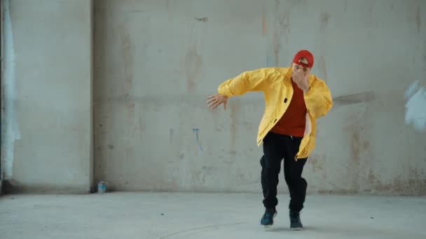 Kaukázusi hipszter show-k, vagy utcai, városi léptek gyakorlása. Fiatal stílusos break táncos mozog, miközben mozog lépésben a hip-hop zene. Kültéri sport 2024. Szürke háttér. hiphop. - Felvétel, videó