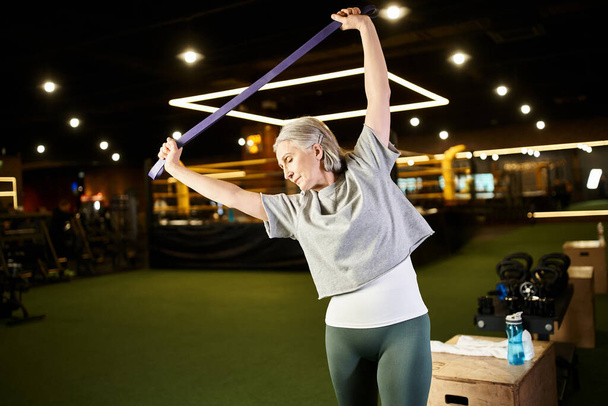 radosna seniorka w wygodnym ubraniu ćwicząca aktywnie na ekspanderze fitness podczas treningu siłowego - Zdjęcie, obraz
