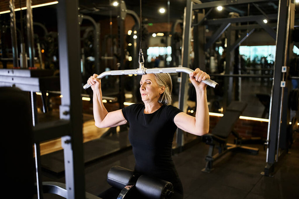 krásný atletický zralý žena v útulný oblečení cvičení aktivně s lats pulldown stroj v tělocvičně - Fotografie, Obrázek