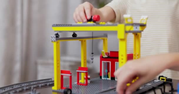 Skupione dziecko montujące model żurawia budowlanego z kolorowego zestawu blokowego, przedstawiającego miniaturowy plac budowy. Wysokiej jakości materiał 4k - Materiał filmowy, wideo