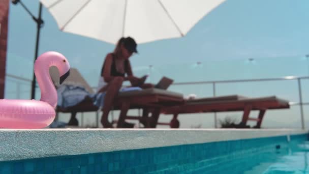 Жінка-фрілансер, що працює онлайн на даху басейну в купальнику. Концепція віддаленої роботи - Кадри, відео