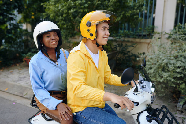 Посміхаючись Чорна жінка використовує послугу таксі мотоцикла при переїзді по місту - Фото, зображення