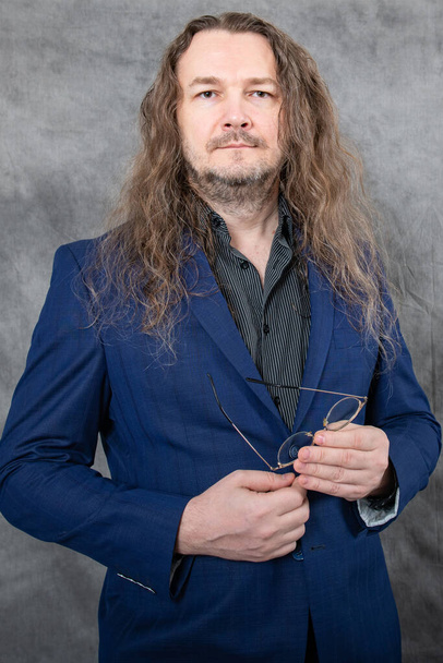 Ein selbstbewusster Mann mit langen Haaren zeigt elegant verschiedene professionelle Posen in einem modischen blauen Anzug, der Stil und Vielseitigkeit ausstrahlt, geeignet für geschäftliche oder modebezogene visuelle Inhalte. - Foto, Bild