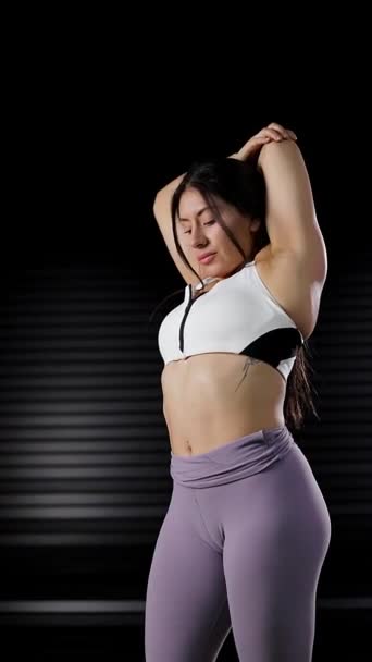 pystysuora video nainen venyttely kätensä jälkeen hänen harjoitus yllään urheiluvaatteet - Materiaali, video