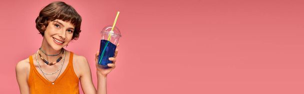 feliz joven con el pelo corto morena celebración refrescante bebida de verano sobre fondo rosa, pancarta - Foto, Imagen