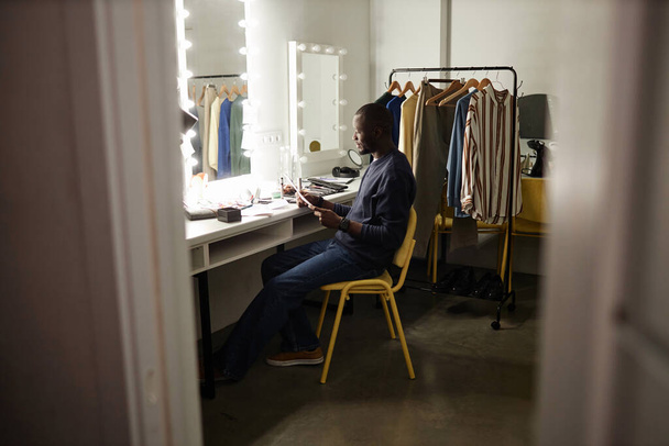 Wide angle shot of Black adult man reading script and rehearsing lines backstage copy space - Fotó, kép