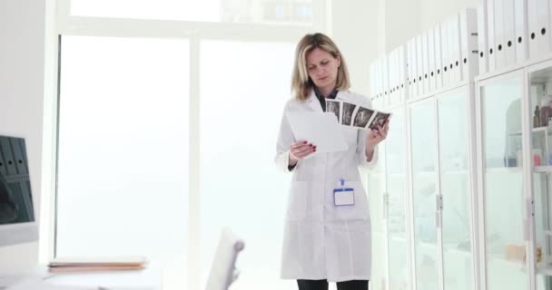 Γυναίκα γιατρός κοιτάζοντας τα ιατρικά έγγραφα των ασθενών και τα αποτελέσματα των δοκιμών στον υπολογιστή 4k ταινία αργή κίνηση. Εργασία του ιατρού θεραπευτή έννοια - Πλάνα, βίντεο