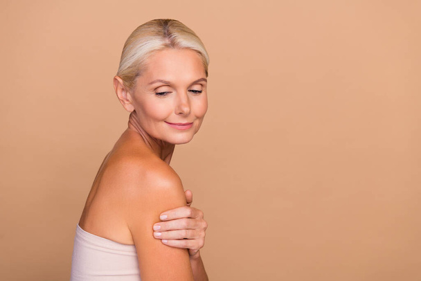Photo of sweet shiny woman naked shoulders embracing herself empty space isolated beige color background. - Foto, immagini