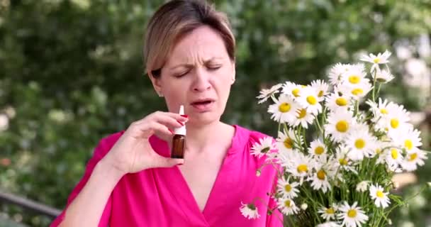 Γυναίκα με αλλεργική ρινίτιδα που μυρίζει χαμομήλι και μύτη που στάζει με σταγόνες σε φιαλίδιο έξω από ταινία 4k. Εποχιακές αλλεργίες και βρογχικό άσθμα έννοια - Πλάνα, βίντεο