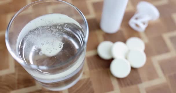 La persona arroja un comprimido blanco en un vaso de agua. Concepto de vitaminas hidrosolubles - Imágenes, Vídeo