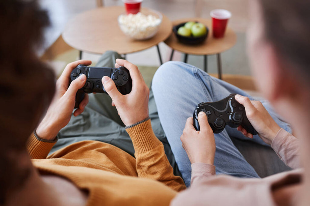 Vue du dessus d'un jeune couple méconnaissable jouant à des jeux vidéo ensemble et tenant des contrôleurs - Photo, image