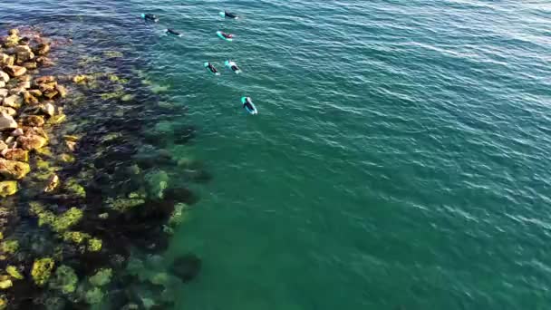 Szörfiskola Spanyolország tengerpartján. Különböző emberek tanulnak szörfözni és gyakorolnak a vízen. Kiváló minőségű 4k felvételek. - Felvétel, videó