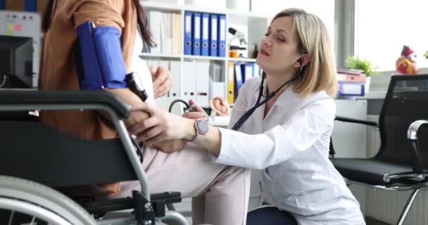 Femme médecin mesure la pression artérielle de la patiente enceinte en fauteuil roulant. Grossesse et maternité en fauteuil roulant concept - Séquence, vidéo