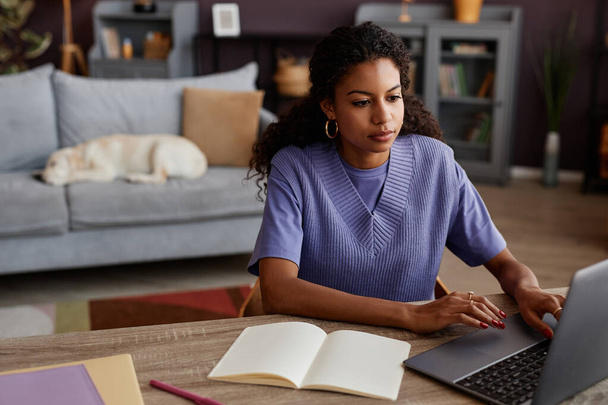 Portré fekete fiatal nő dolgozik otthonról, és használja laptop kutya alszik a háttérben, másolja a helyet - Fotó, kép
