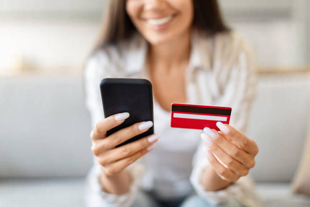 Recortado de la señora que sostiene una tarjeta de crédito y un teléfono inteligente, significa conveniencia y tecnología en las compras modernas - Foto, imagen