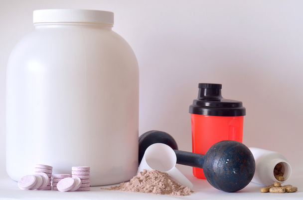 Big jar of protein powder, dumbbell, shaker, pills and tablets - Fotó, kép