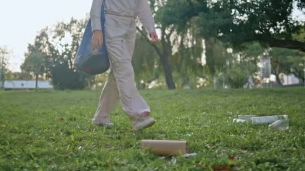 Mujer voluntaria caminando parque entre la contaminación de la basura. Chica conservacionista pisando hierba verde contaminada por la basura con bolsa ecológica. Lanzamiento casual de residuos plásticos que afectan profundamente al medio ambiente. - Imágenes, Vídeo