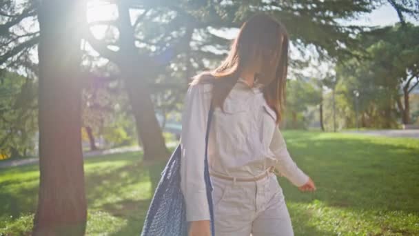 Boldog hölgy sétáló természet nyugodt, nyugodt környezetben. Wellness-központú alkalmi nő nyugalmat talál a zöld napos parkban. Mosolygó lány séta a napfényben élvezi egyszerűség hétvégi szabadidő. - Felvétel, videó