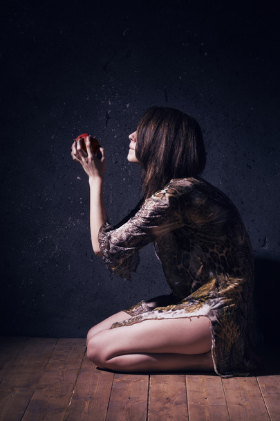 Femme folle solitaire avec pomme rouge assise sur un sol
 - Photo, image
