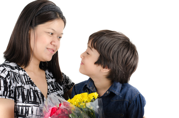 Μικρό αγόρι, φιλώντας τη μητέρα του με λουλούδι σε άσπρο φόντο - Φωτογραφία, εικόνα