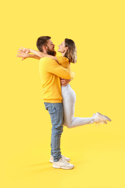 Happy couple in love hugging on yellow background - Photo, Image